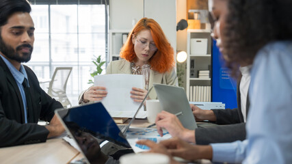 Multi-ethnic business team in office meeting, reviewing documents and brainstorming innovative ideas for a new business venture and strategy.