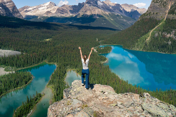 Triumph on the peak: Woman celebrates reaching mountain summit with view.