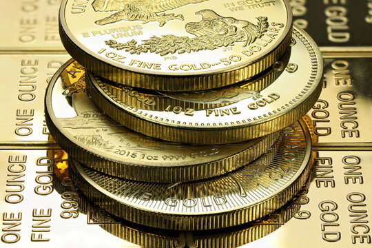 4 different 1 ounce gold bullion coins on a layer of gold ingots