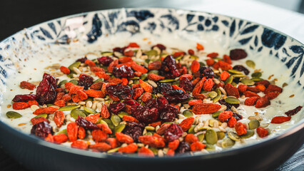 Beautiful healthy yogurt bowl with pumpkin seeds, goji berries, chia seeds, dried cranberries and other superfoods. Nutritious breakfast or snack for wellness lifestyle.
