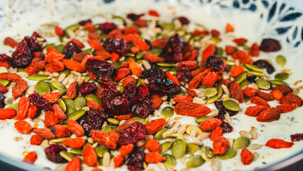 Beautiful healthy yogurt bowl with pumpkin seeds, goji berries, chia seeds, dried cranberries and other superfoods. Nutritious breakfast or snack for wellness lifestyle.