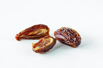 Cut and whole medjool dates isolated against a white background.