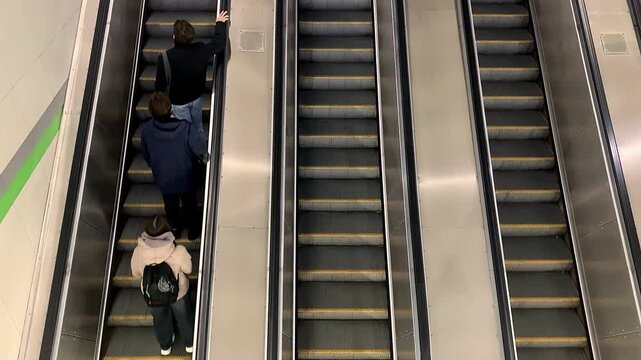 Big city concept, underground escalator with people. People are riding an escalator in an underground metro passage.