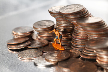 Tiny man figurine surfing a wave of quarters