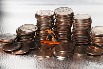 Tiny man figurine surfing a wave of quarters
