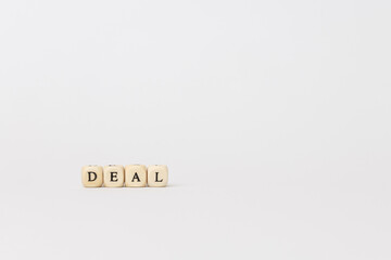 Wooden letter blocks spelling deal on a minimalistic white background, symbolizing business agreements and professional negotiations. copy space
