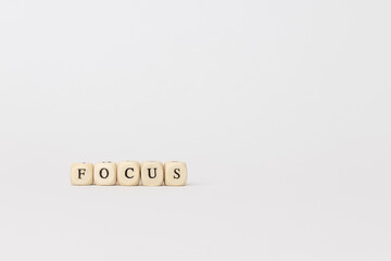 Wooden blocks spelling the word focus on a minimalistic background, representing clarity, concentration, and mindfulness in daily life. copy space