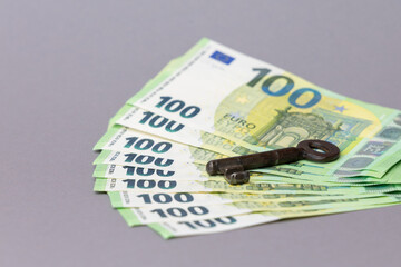 Stacks of hundred euro banknotes with an antique key placed on top, symbolizing finance, security, and investment opportunities. copy space