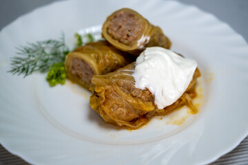 Stuffed cabbage rolls on a plate with sour cream