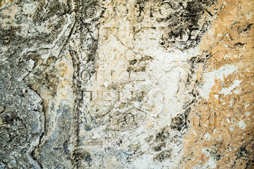 ancient stone wall texture with ancient script and slphabets. texture of ancient Roman archaeological site