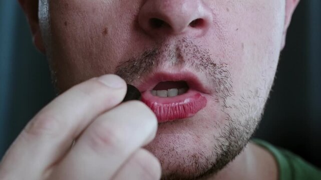 Close up of a man with a beard applying red lipstick on his lips, equal 