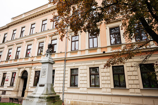 Historic building in Tarnow Poland with J&oacute;zef Jerzy Karol Szujski statue on a pedestal and autumn trees in front