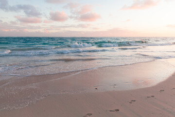 A tranquil beach scene at sunset featuring clear blue water