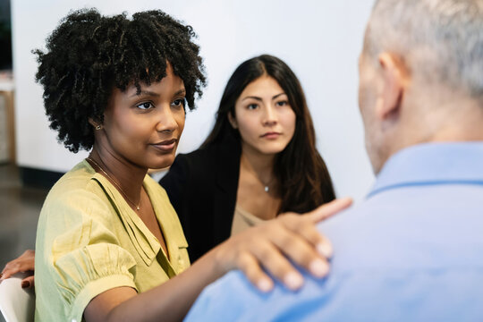 Diverse people gathered in a group therapy session at a community center, supporting each other through open conversation and empathy. Mental health, emotional care, and community support.