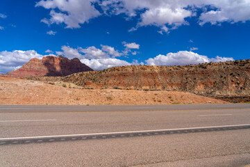 Desert highway leads to red rock mountains under blue sky.