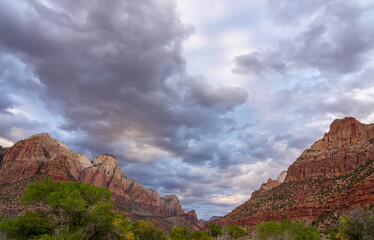 Dramatic clouds gather over Zion National Park sandstone cliffs.