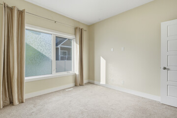 Large window in a white room with a tan curtain