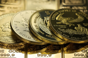 4 different 1 ounce gold bullion coins on a layer of gold ingots