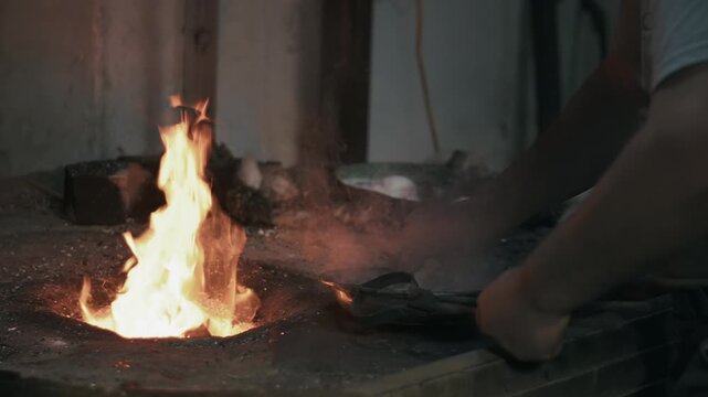 Elderly man in his workshop plates the copper bowl with tin. Tinsmith covering the copper object with tin over fire