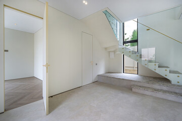 Bright and spacious modern interior featuring a glass staircase and minimalist design in a contemporary home