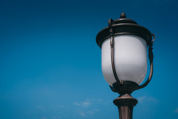 Vintage street lamp against clear blue sky illuminating urban scene with classic design and...