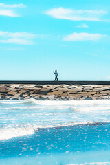 九十九里浜の夏空と防波堤を歩く人