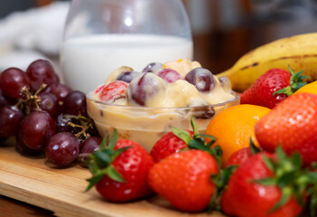 Fresh Fruit Salad with Milk and Whole Fruits on Wooden Table. Healthy Food Concept