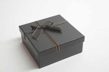 Design background. Black box with black ribbon and gold threads. Suitable for Black Friday advertising.