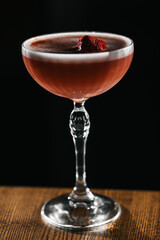 Elegant red cocktail with a berry garnish in a crystal glass on a wooden table. Sophisticated drink, luxury bar atmosphere, fine mixology and stylish presentation.