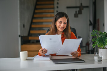Fototapeta premium Woman reading documents smiling working from home office