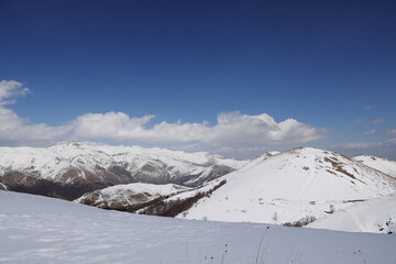 Snow-covered mountain slope with distant peaks under bright blue sky, Lori, Armenia
