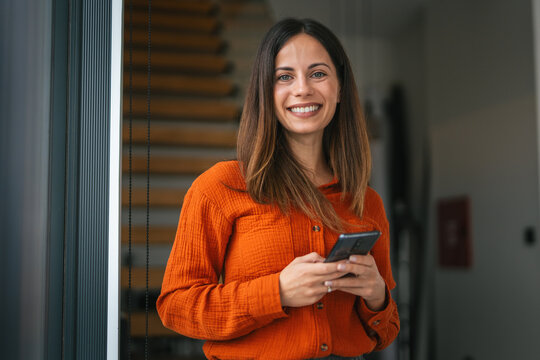 Happy woman smiling looking camera holding smart phone