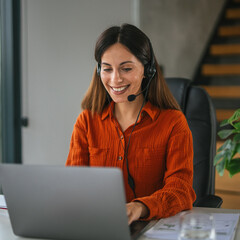 Woman wearing headset working on laptop, remote support