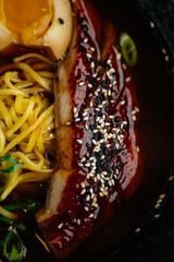 Close-up of Japanese ramen with noodles, marinated egg, grilled pork topped with sesame seeds and rich broth. Traditional Asian comfort food, gourmet cuisine concept.
