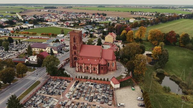 Epic drone circle of the historic, brick Church of St. Jadwiga in Pępowo, Wielkopolska, captured in warm colors of early autumn.