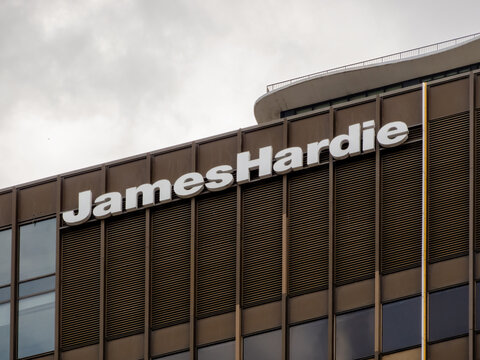 Chicago, Illinois, USA. Oct 21, 2025. The "James Hardie" logo in white, prominently displayed on a modern brown building facade with vertical architectural details, under a cloudy sky.