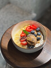 Yogurt granola fruit bowl with peanut butter, banana, strawberries and blueberries, top view, sunlight