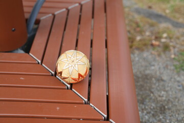 A gold colored ball sits on a wooden bench