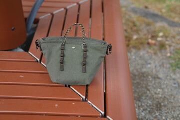 A small purse is sitting on a wooden bench