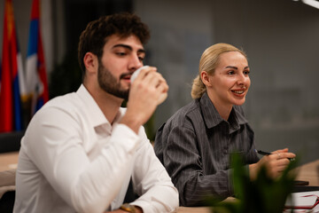 Business professionals collaborating at office meeting, man drinking coffee