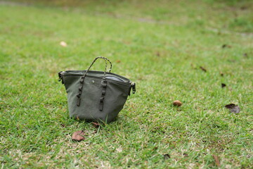 A green purse is laying on the grass