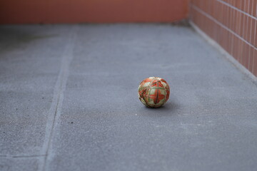 A small orange ball is sitting on a grey concrete floor