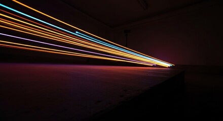 Vibrant colored light trails streak through a dark room, creating abstract, dynamic patterns