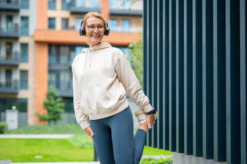 Senior woman stretching leg before workout outdoors