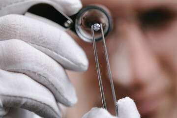 Closeup Caucasian male jeweler examining diamond with loupe in detail