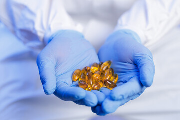 Scientist hold omega fish oil yellow capsules in protective blue gear, pharmaceutical lab workshop