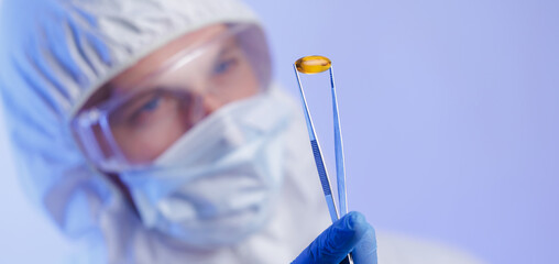 Medical worker examining fish oil yellow capsules in laboratory. Quality in production pharmacology...