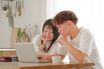 パソコンを見ながらお金の管理を行う夫婦