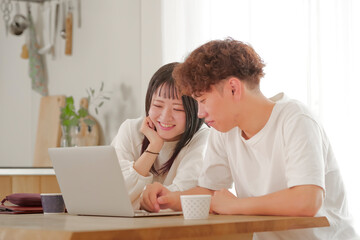 パソコンを見ながらお金の管理を行う夫婦