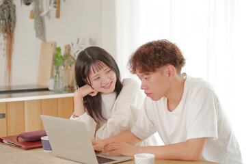 パソコンを見ながらお金の管理を行う夫婦